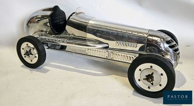 une maquette en métal d'une voiture de course posée sur une surface blanche