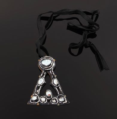 a silver necklace with a triangle shaped pendant on a black background