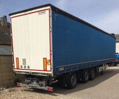 un semi-remorque bleu et blanc garé dans une allée