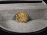 une pièce d'or posée dans une boîte contenant un stylo