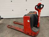 a red forklift in a garage with a garage door in the background