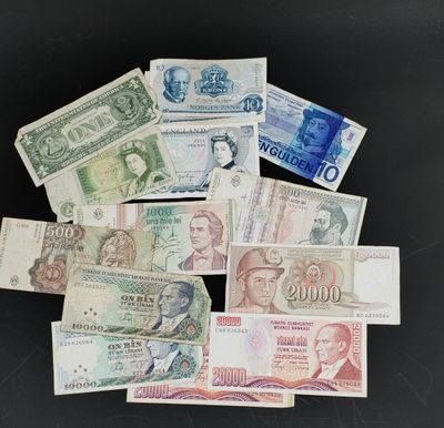 Plusieurs billets de banque de différentes valeurs sont empilés sur une surface noire