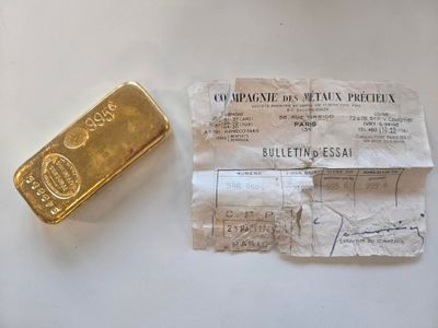 un lingot d'or et un reçu posés sur une table blanche, avec un bout de papier
