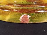 a close up of a yellow and green bowl on a black surface