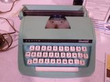 une machine à écrire bleue posée sur un bureau, à côté d'un ordinateur
