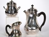 deux théières en argent et une cafetière posées sur une table