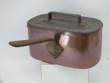a small copper pot with a wooden spoon in it