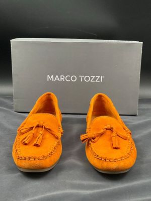 une paire de mocassins orange avec une boîte en arrière-plan