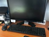 un écran d'ordinateur, un clavier, une souris et un magazine posés sur le bureau