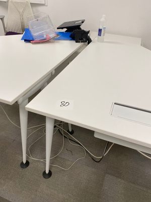 two white desks with computers on them in an office
