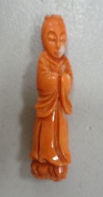 an orange jade buddha figurine on a white surface
