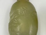 a green glass bottle with a red lid on a white surface