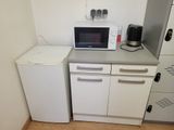 a small kitchen with a microwave, refrigerator, and refrigerator freezer