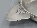 a silver bowl with a leaf decoration on it