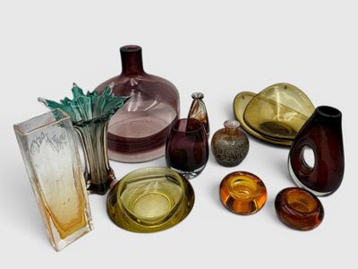 many different colored glass vases and plates on the table