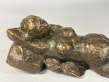a bronze statue of a cat laying on a pillow