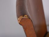 a close up of a wooden chair with a gold ring on it