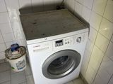 a washer and dryer in the corner of a tiled room