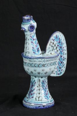 un petit poulet bleu et blanc dans un bol, sur fond noir