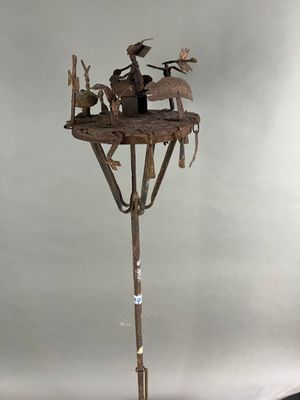 une sculpture représentant un homme assis au sommet d'un arbre