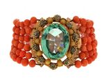 a close up of a bracelet with a green stone and orange beads