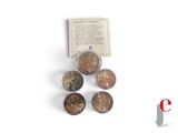 several coins are sitting next to a book on a white surface