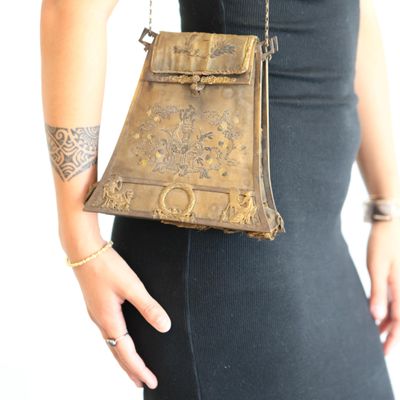 woman in a black dress holding a brown purse with a chain around it