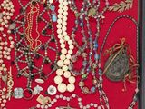 a shadow box filled with assorted necklaces and other items
