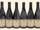 six bouteilles de vin sont alignées sur une surface blanche