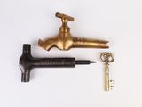 a brass faucet and a key on a white surface