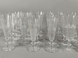 six verres à vin transparents sont alignés sur une surface blanche