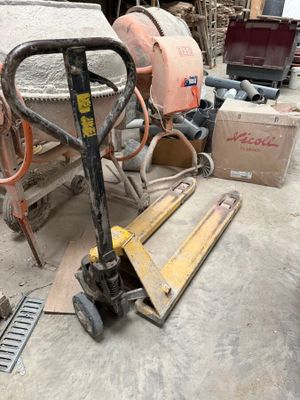 un chariot élévateur qui se trouve au sol, à côté d'une pile de cartons