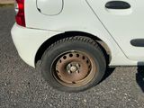 une petite voiture blanche avec un pneu crevé dans la rue