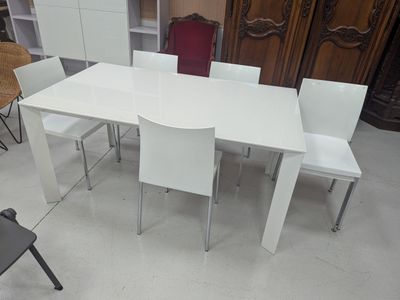 une table blanche avec quatre chaises et un meuble en arrière-plan