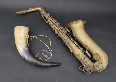 an old saxophone and horn are sitting on a black surface