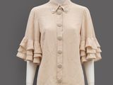 an image of a mannequin wearing a beige shirt with ruffled sleeves