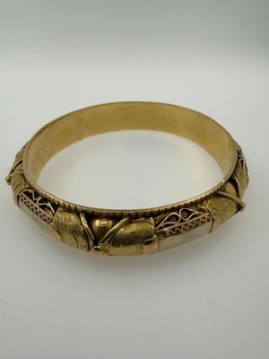 a close up of a gold bracelet on a white surface