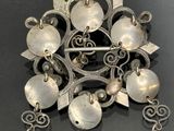 an antique silver broochle on a black surface with a black background