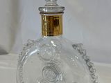 a clear glass bottle with a gold top on a white surface