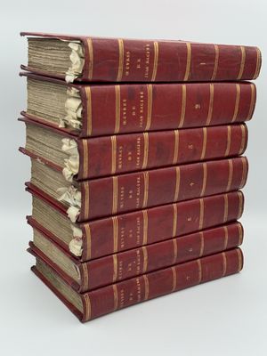six livres rouges empilés les uns sur les autres sur une surface blanche