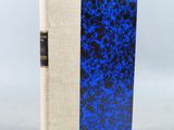 un livre à la couverture bleue posé sur une table blanche