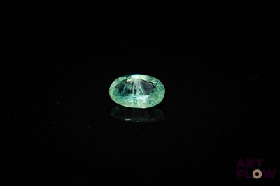a close up of a green diamond on a black surface
