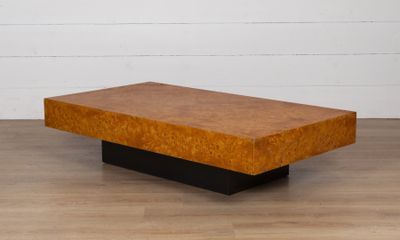une table basse en bois avec un piètement noir posée sur un parquet