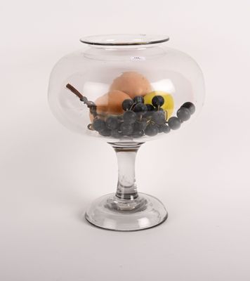 un saladier en verre rempli de fruits et de noix posé sur un plan de travail blanc