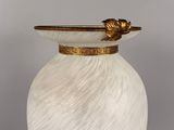 a white vase with a gold rim on a table