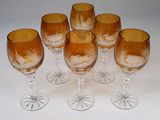 six verres à vin ornés de motifs gravés, posés sur une surface blanche
