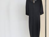 a black dress hanging on a clothes rack in front of a white wall