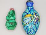 trois objets en verre de couleurs différentes sont disposés sur une surface blanche