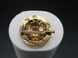 yellow gold and diamond broochle on display in a display case