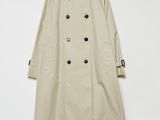 a beige trench coat hanging on a white wall